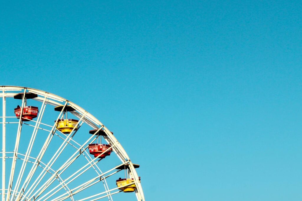 Iconic Ferris wheel at Santa Monica Pier beneath a bright blue sky, perfect for summer travel imagery.